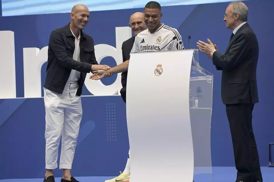 Kylian Mbappe bersalaman dengan Zinedine Zidane dan mendapat tepuk tangan dari Presiden Real Madrid Florentino Perez saat diperkenalkan kepada penggemar di stadion Santiago Bernabeu di Madrid, Selasa, 16 Juli 2024.
